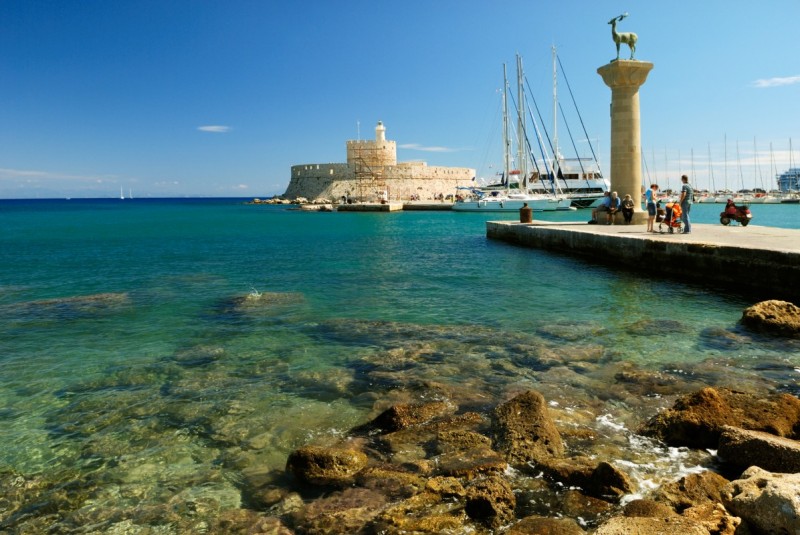 Yachts medieval statue of deer and old lighthouse in the harbor of Rhodes shutterstock 21519544